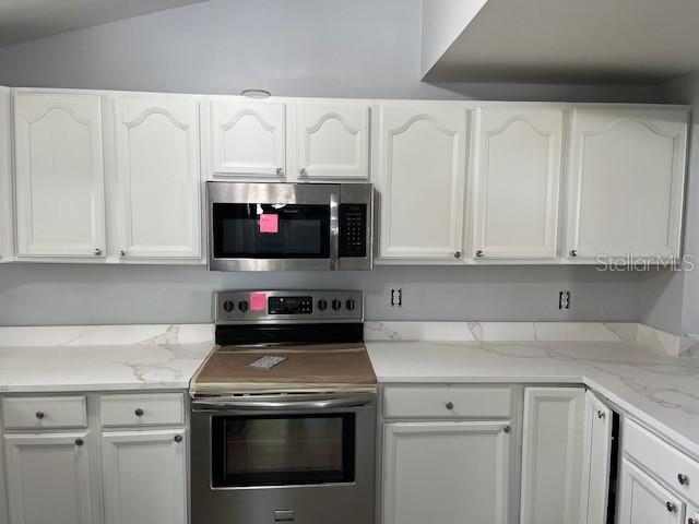 A kitchen features white cabinets, stainless steel appliances, and white marble-patterned countertops — 1702 N GORDON STREET, PLANT CITY, FL
