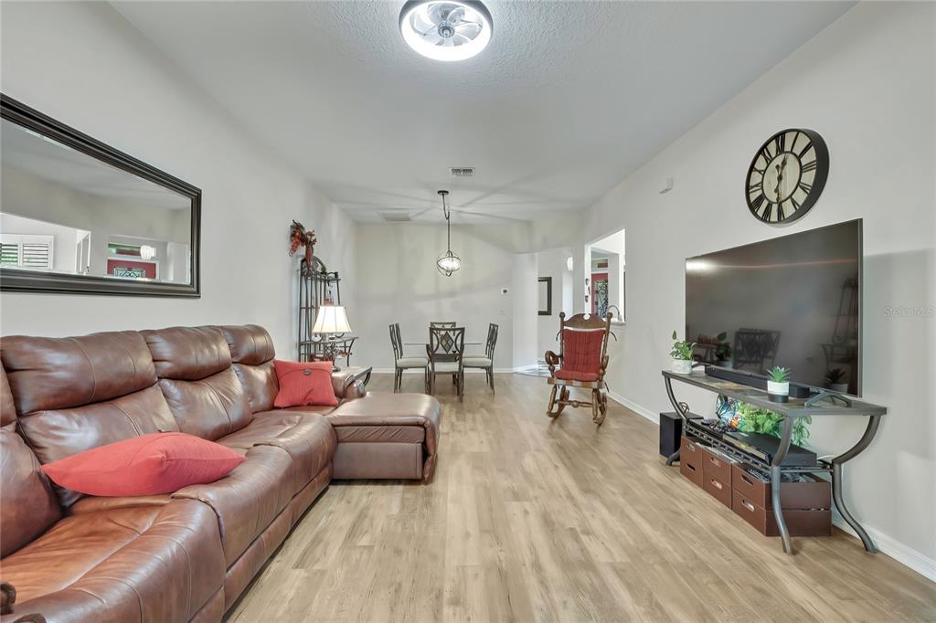 A living room with a brown leather sectional, dining area, and television on a stand — 15036 SILVERSMITH CIRCLE, SPRING HILL, FL