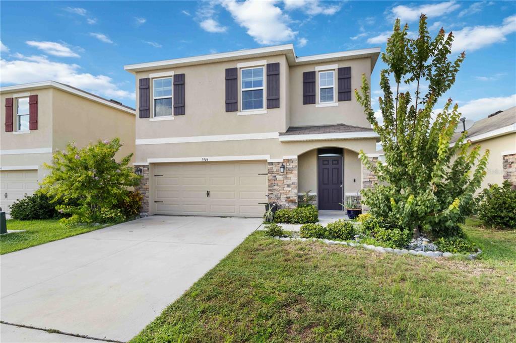 A two-story suburban house features a tan stucco exterior, stone accents, and a two-car garage — 5904 SILVER SAGE WAY, SARASOTA, FL