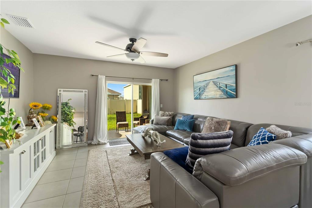 A living room features a gray sectional sofa, a coffee table, and a sliding glass door — 5904 SILVER SAGE WAY, SARASOTA, FL