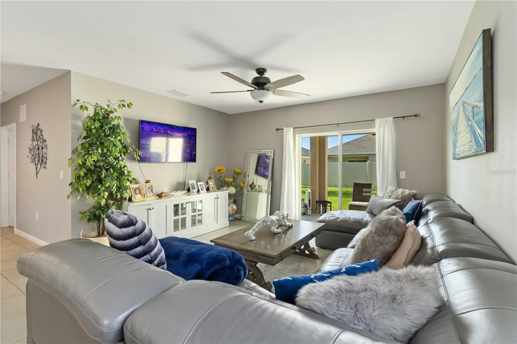 A living room features a grey sectional sofa, a white media console, and a ceiling fan — 5904 SILVER SAGE WAY, SARASOTA, FL