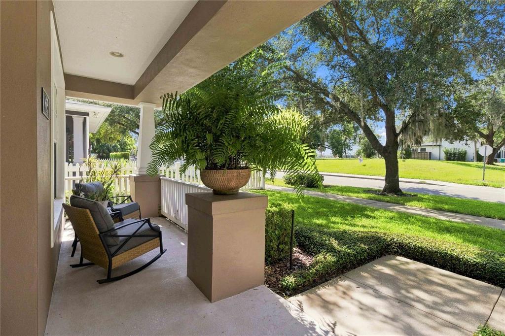 A covered front porch features a rocking chair, a potted fern, and a white fence — 615 E KALEY STREET, ORLANDO, FL