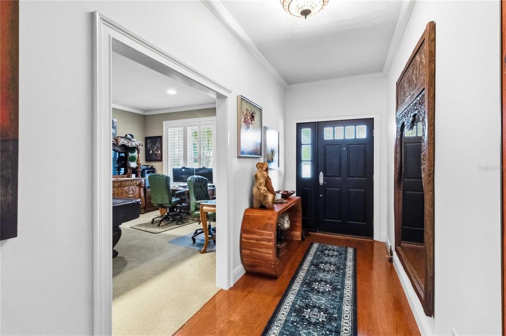 A foyer with hardwood floors, a dark front door, and an entryway to an office — 615 E KALEY STREET, ORLANDO, FL