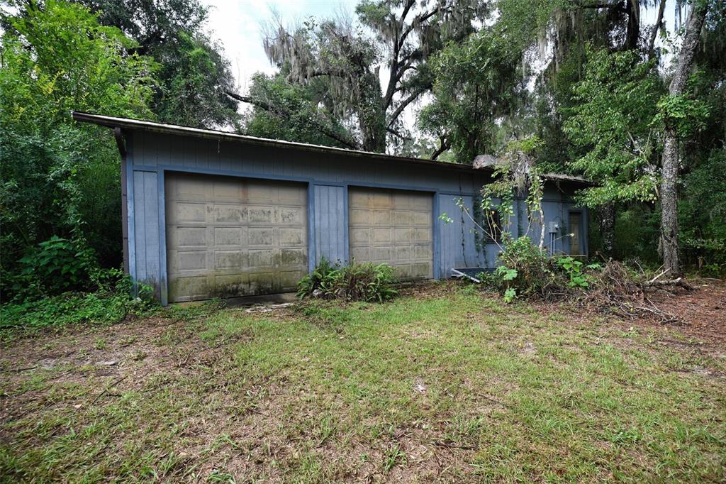 A sunroom features wood walls, a ceiling fan, a ladder, and large windows overlooking trees — 2424 NE 170TH STREET, CITRA, FL
