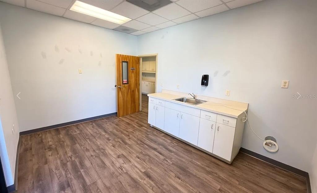 A small office room features light blue walls, wood-look flooring, and a white sink cabinet — 9401 SW HIGHWAY 200 UNIT 600, OCALA, FL