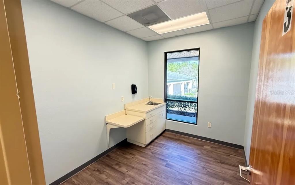 A small office or exam room features light blue walls, wood-look flooring, and a sink — 9401 SW HIGHWAY 200 UNIT 600, OCALA, FL