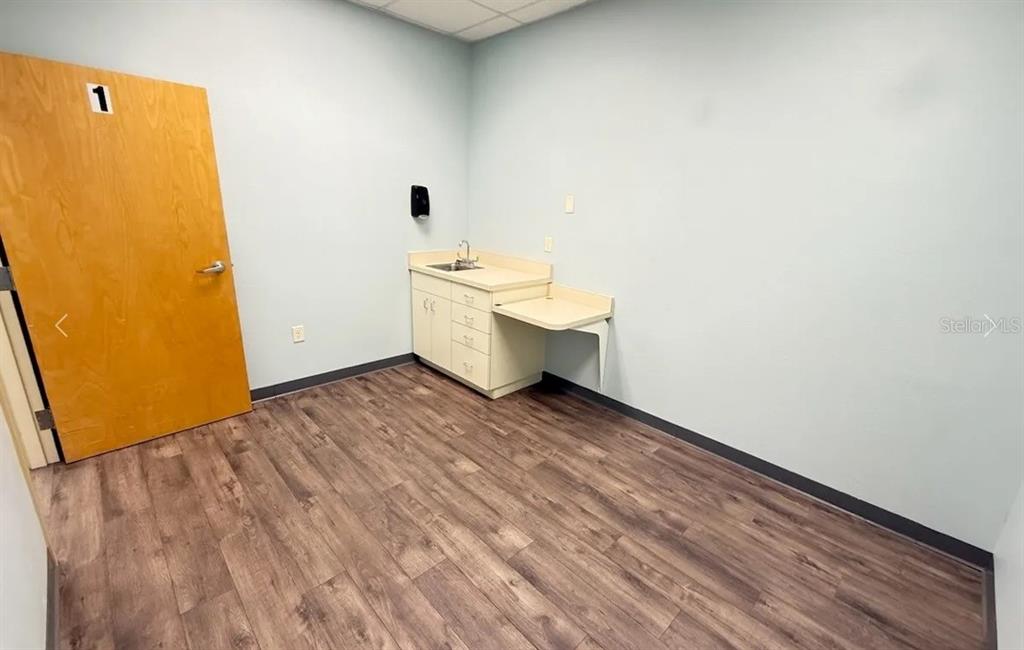 A small room with light blue walls, wood-look flooring, and a built-in cabinet with a sink — 9401 SW HIGHWAY 200 UNIT 600, OCALA, FL