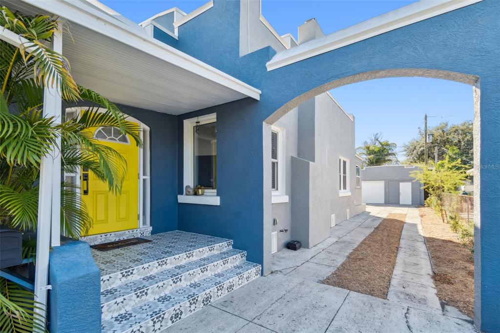 A blue house exterior features a bright yellow front door and patterned tile porch steps — 1120 17TH AVENUE N, ST PETERSBURG, FL