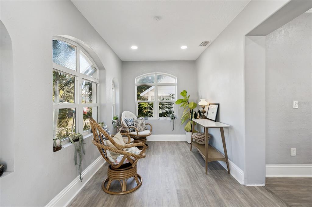 A sunroom with light gray walls, wood-look flooring, two rattan chairs, and large arched windows — 1120 17TH AVENUE N, ST PETERSBURG, FL