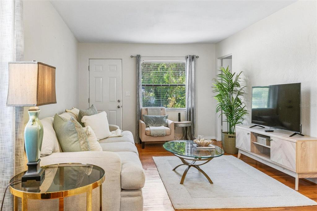 A living room features a beige sofa, glass coffee table, television console, and a window — 5762 2ND AVENUE N, ST PETERSBURG, FL
