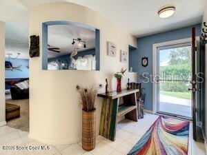 An entryway features a curved wall with a cutout, a console table, and a glass door — 205 RITA BOULEVARD, MELBOURNE BEACH, FL