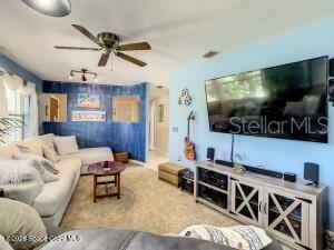 A living room features a large sectional sofa, a wall-mounted television, and a ceiling fan — 205 RITA BOULEVARD, MELBOURNE BEACH, FL