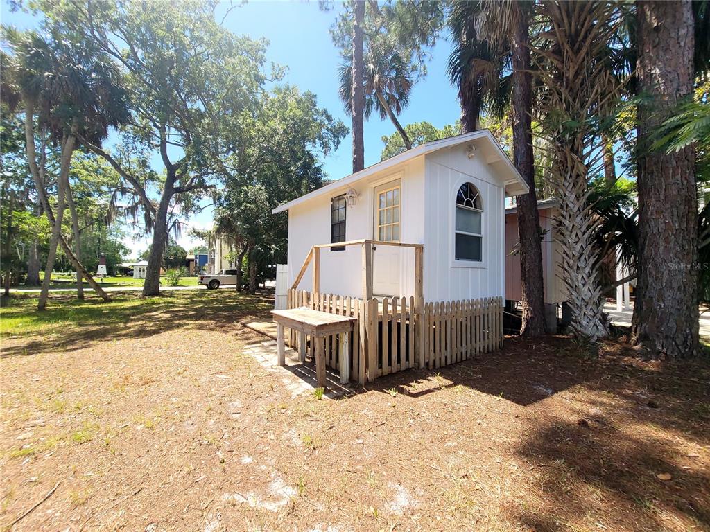 A small white shed with a wooden porch and picket fence stands among trees — 000 SE 245TH STREET, SUWANNEE, FL