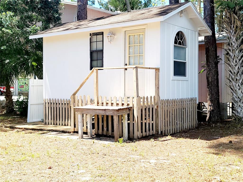A small white shed with a wooden porch and picket fence sits among pine trees — 000 SE 245TH STREET, SUWANNEE, FL