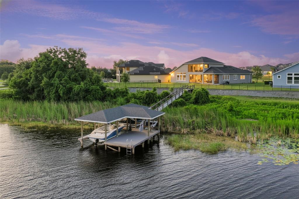 A boat dock with a covered slip sits on a lake in front of houses — 17060 SECRET HOLLOW LOOP, CLERMONT, FL