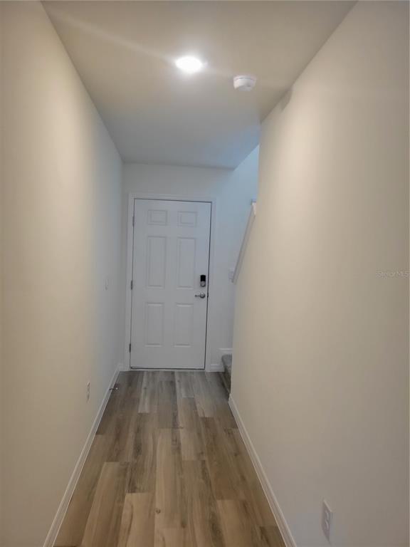 A narrow hallway with light wood-look flooring leads to a white front door — 6534 SW 82ND LOOP, OCALA, FL