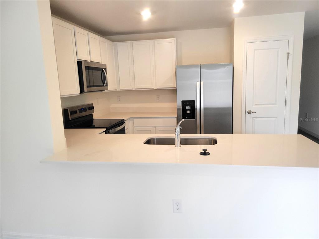 A kitchen features white cabinets, stainless steel appliances, and a breakfast bar with a sink — 6534 SW 82ND LOOP, OCALA, FL
