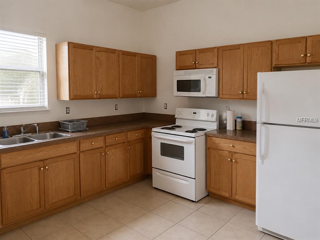 A kitchen features light wood cabinets, brown countertops, white appliances, and beige tile flooring — 1440 PRESCOTT STREET S, ST PETERSBURG, FL