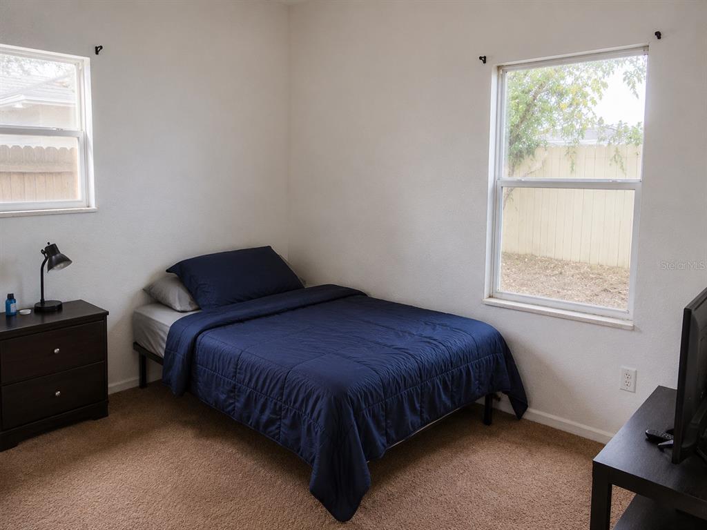A bedroom features a bed with blue bedding, a dark dresser, and two windows — 1440 PRESCOTT STREET S, ST PETERSBURG, FL