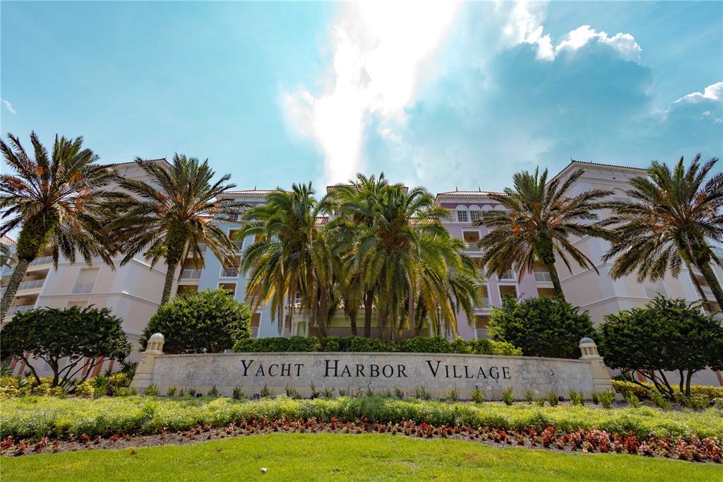 A low-angle exterior view of the Yacht Harbor Village building with palm trees and landscaping — 8 SCHOONER CIRCLE, PALM COAST, FL