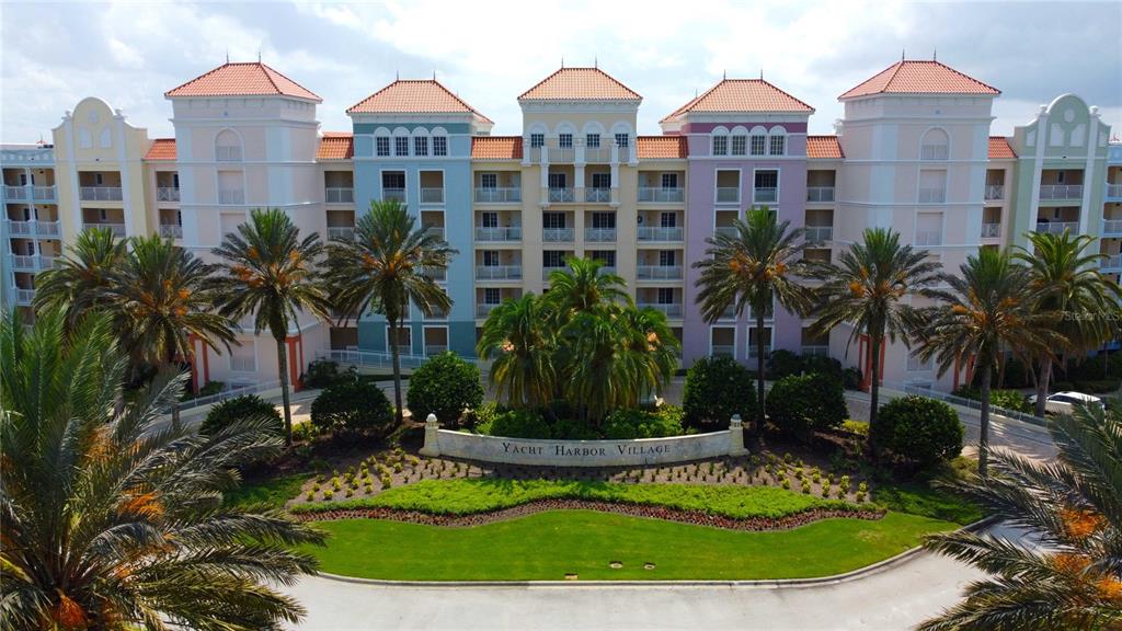 An exterior view of a multi-story apartment complex with palm trees and a landscaped entrance — 8 SCHOONER CIRCLE, PALM COAST, FL