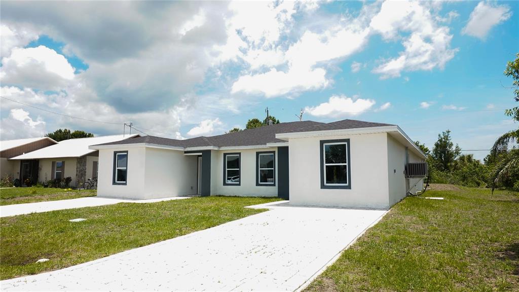 A single-story house with white stucco walls, dark window frames, and a paved driveway — 24 TROUT WAY, KISSIMMEE, FL