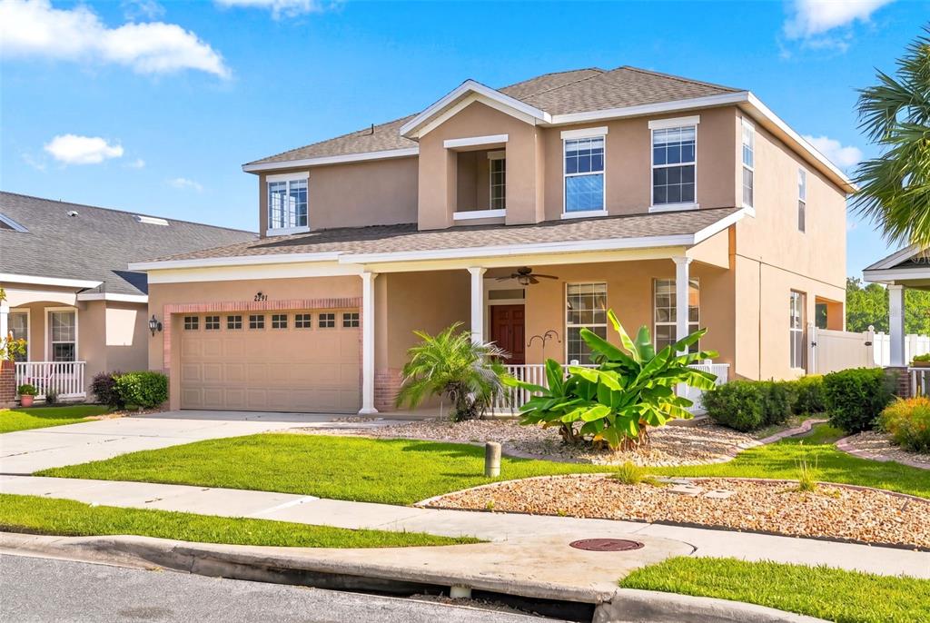 A two-story suburban house with a tan stucco exterior, a front porch, and a garage — 2391 SABASTIAN ST, MOUNT DORA, FL