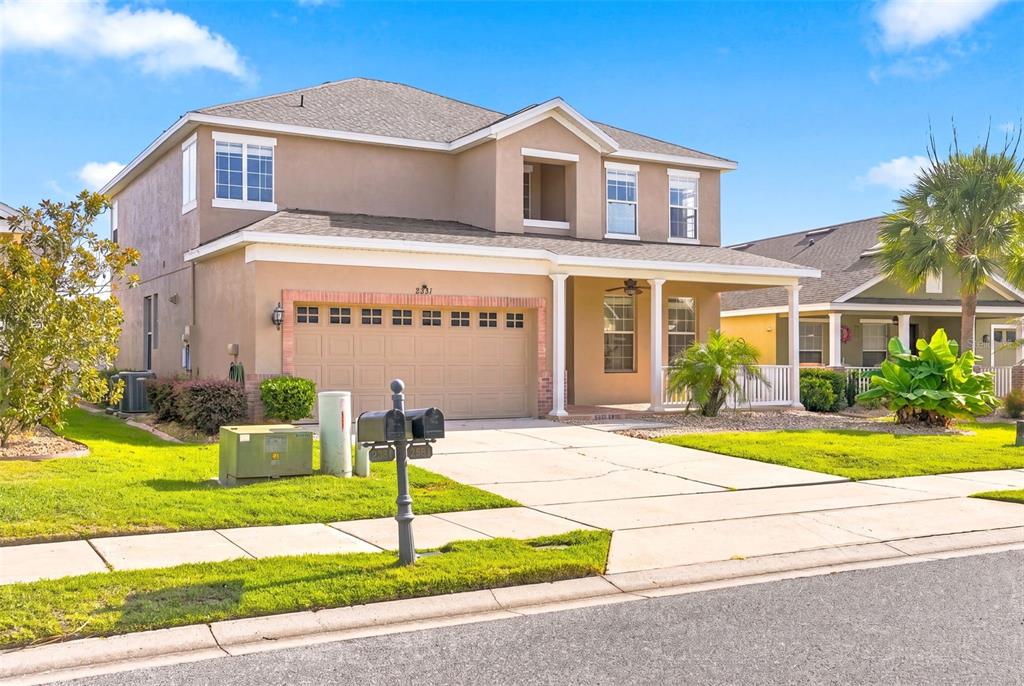 A two-story suburban house with a tan stucco exterior, a two-car garage, and a porch — 2391 SABASTIAN ST, MOUNT DORA, FL