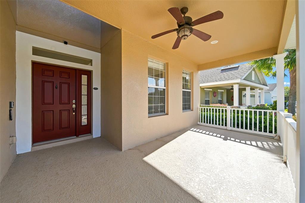 A covered front porch features a red door, a ceiling fan, and a white railing — 2391 SABASTIAN ST, MOUNT DORA, FL