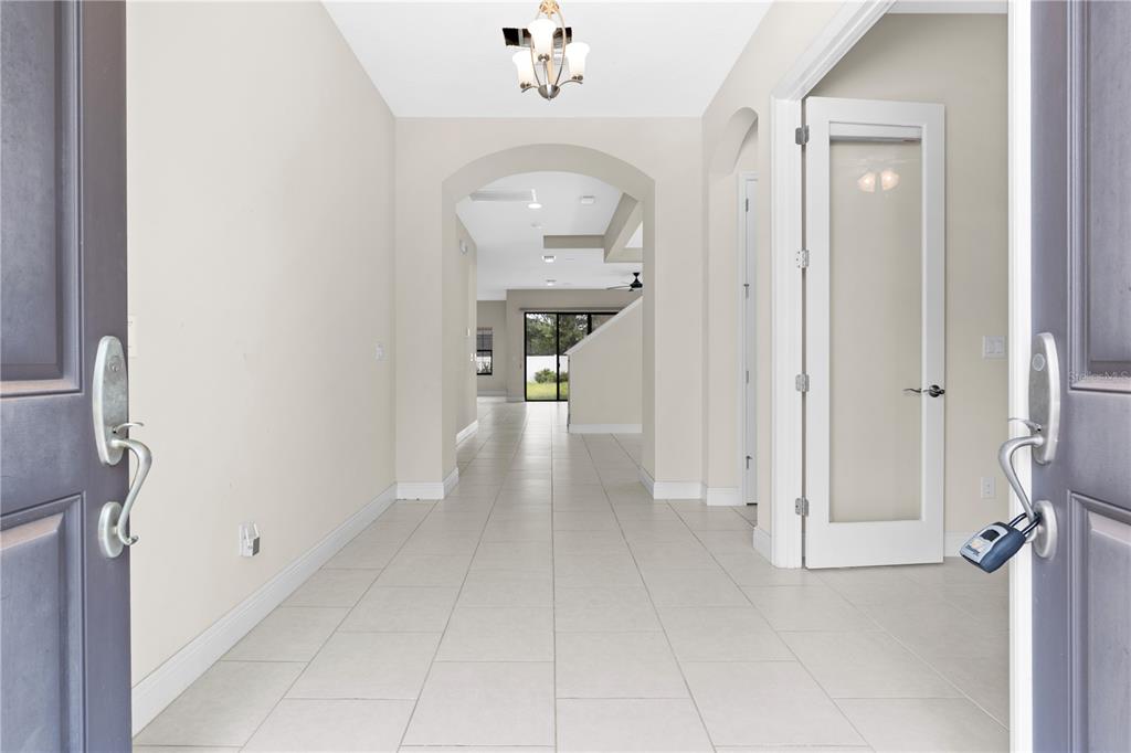 A view through an open front door into a tiled entryway with an arched hallway — 13830 MOONSTONE CANYON DRIVE, RIVERVIEW, FL