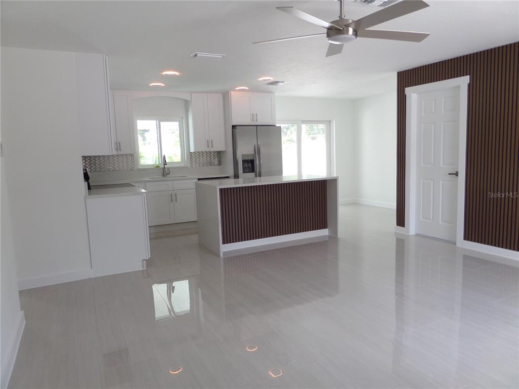 A modern kitchen features white cabinets, stainless steel appliances, and a wood-slatted kitchen island — 4925 SILK OAK DRIVE, SARASOTA, FL
