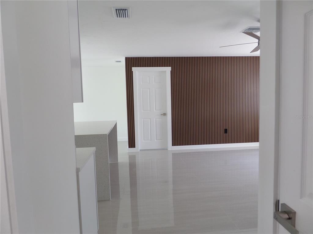 A room with light tile flooring, a white door, and a brown slatted accent wall — 4925 SILK OAK DRIVE, SARASOTA, FL