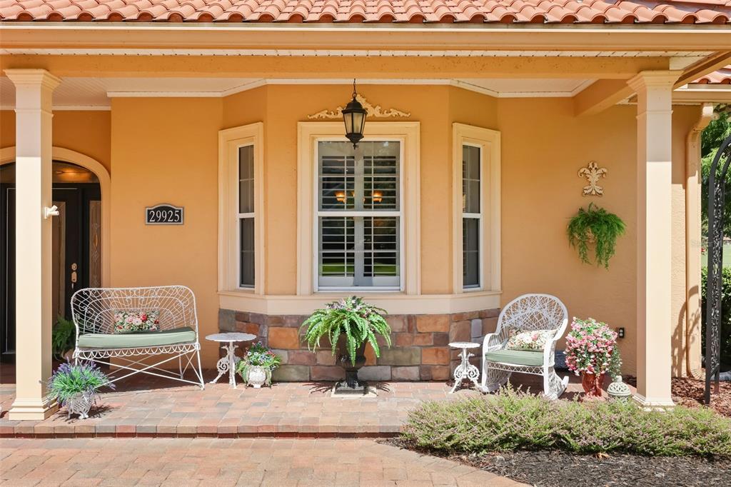 A covered front porch features a brick floor, two white chairs, and a bay window — 29925 CYPRESS POINTE, TAVARES, FL