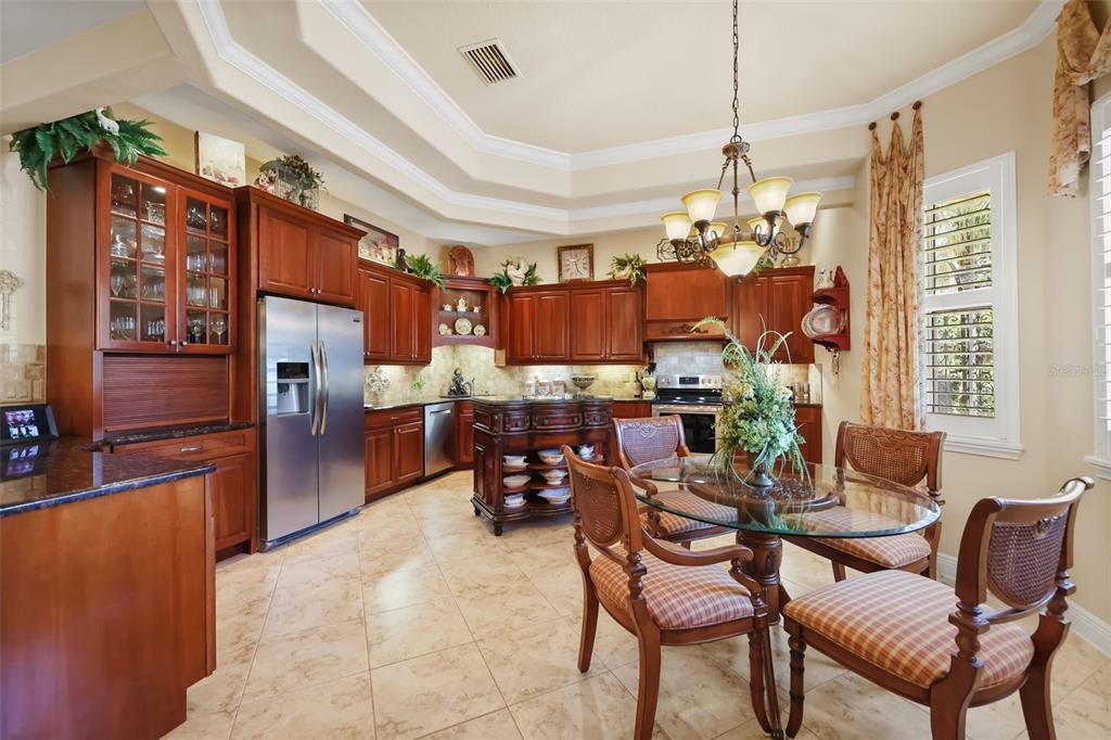 A kitchen with wood cabinets, stainless steel appliances, a center island, and a dining area — 29925 CYPRESS POINTE, TAVARES, FL