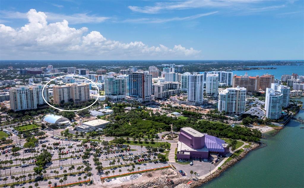 An aerial view shows a tan residential building circled in a coastal city — 750 N TAMIAMI TRAIL UNIT 906, SARASOTA, FL