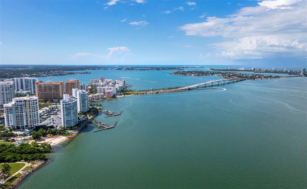 An aerial view shows a coastal city skyline, a long bridge, and a large bay — 750 N TAMIAMI TRAIL UNIT 906, SARASOTA, FL