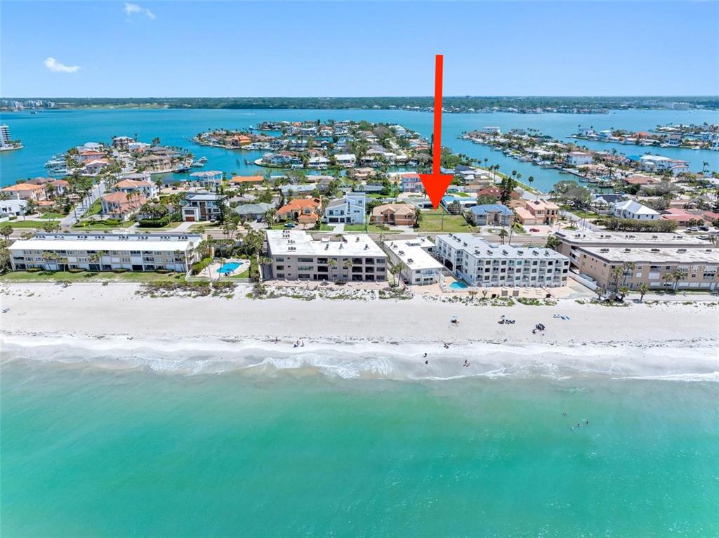 An aerial view shows a vacant beachfront lot marked by a red arrow — GULF BOULEVARD, BELLEAIR BEACH, FL