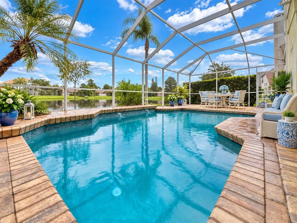 A screened-in swimming pool with a brick paver deck overlooks a lake and neighboring houses — 624 HARDWOOD CIRCLE, ORLANDO, FL