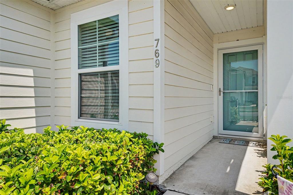 The exterior of a house features light-colored siding, a front door, and a window — 769 GRAND RESERVE DRIVE, BUNNELL, FL