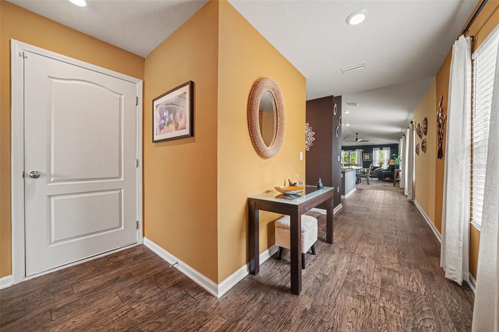 An entryway with wood-look flooring, a console table, and a mirror leads to an open living area — 769 GRAND RESERVE DRIVE, BUNNELL, FL