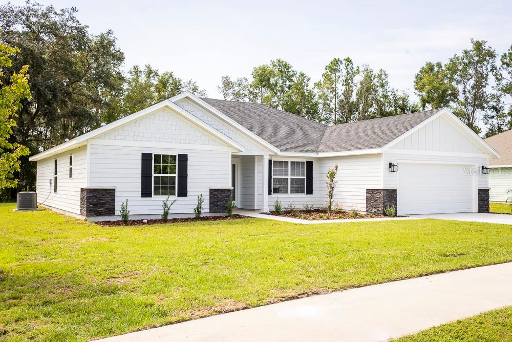 A kitchen island with a granite countertop overlooks a living room with a sofa — 569 SW BELLFLOWER DRIVE, LAKE CITY, FL