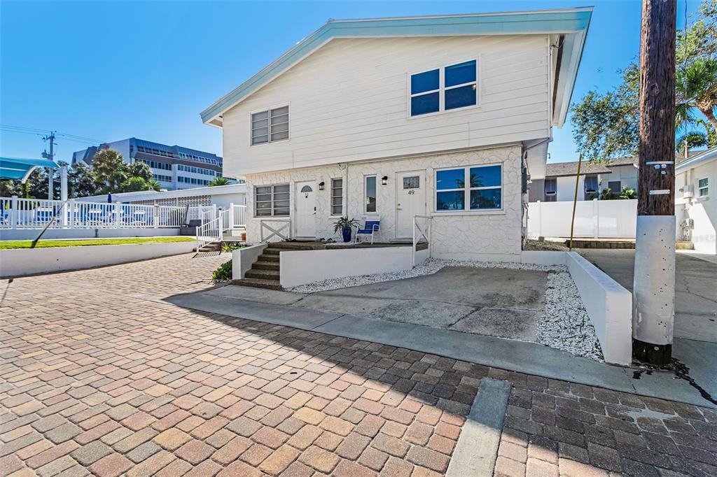 A white two-story building features two front doors numbered 49 and 50 with concrete steps — 6020 MIDNIGHT PASS ROAD UNIT 49, SARASOTA, FL