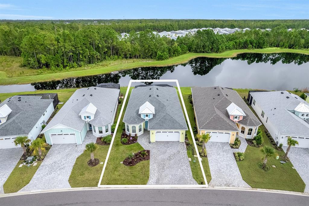 An aerial view of a single-story house with a paved driveway and a backyard pond — 761 MARGARITAVILLE AVENUE, DAYTONA BEACH, FL