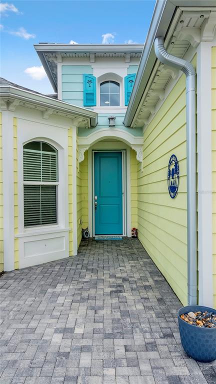 A paved walkway leads to a teal front door on a yellow house with shutters — 761 MARGARITAVILLE AVENUE, DAYTONA BEACH, FL