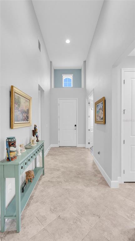 A bright entryway features a tall ceiling, light tile flooring, and a blue accent wall — 761 MARGARITAVILLE AVENUE, DAYTONA BEACH, FL