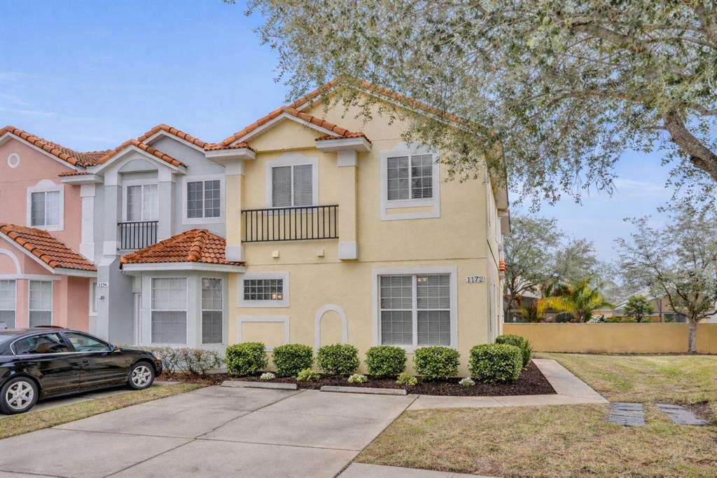 A beige stucco exterior features a white front door, a welcome mat, and small shrubs — 1172 S BEACH CIRCLE, KISSIMMEE, FL