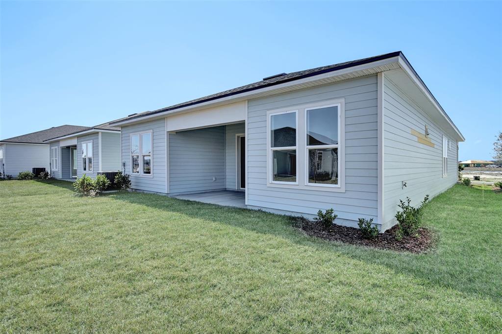 The exterior of a light blue house features a covered patio and a grassy yard — 262 KNOTTED BIRCH AVENUE, ST AUGUSTINE, FL