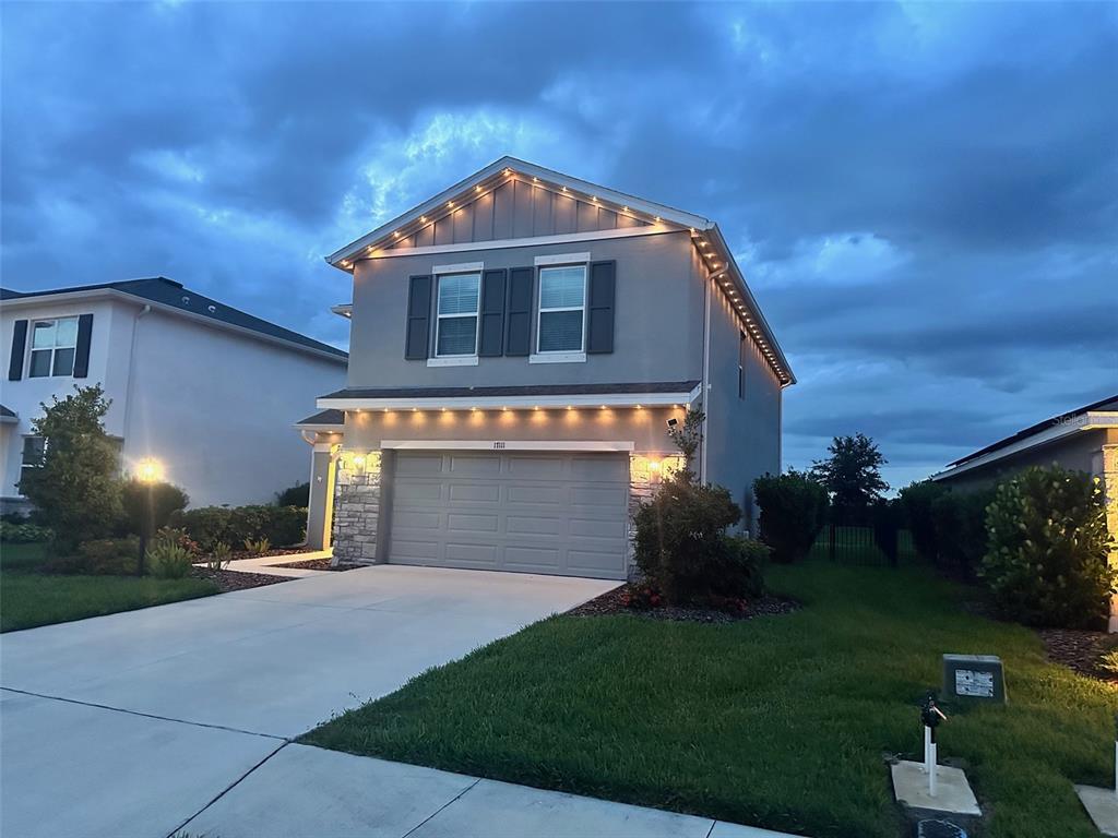 A two-story suburban house with a gray exterior, stone accents, and exterior roofline lighting — 17111 BARNWOOD PLACE, BRADENTON, FL
