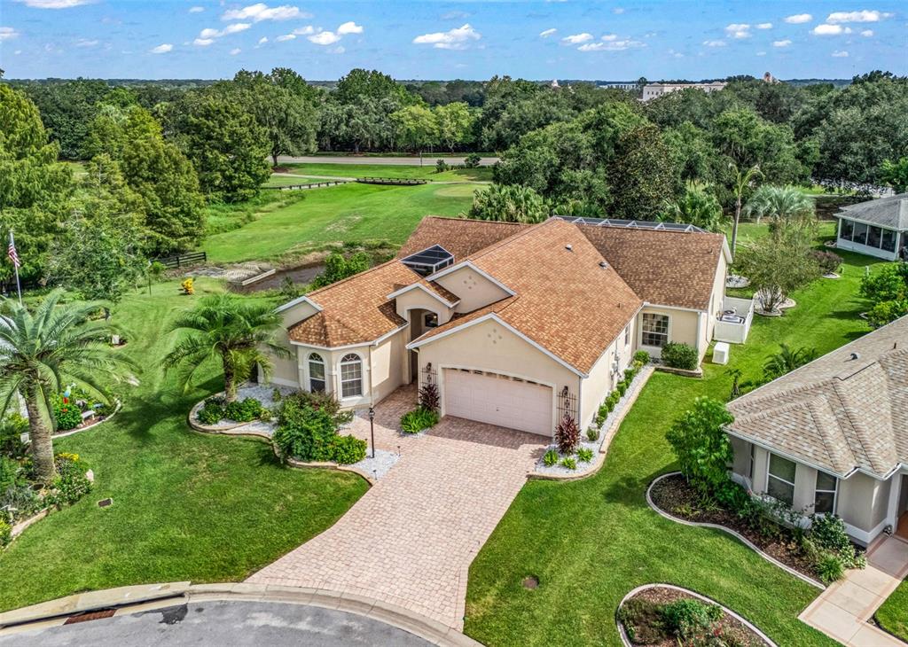 A paved entryway leads to a white garage and a double door with decorative glass — 1802 ESTAFANA WAY, THE VILLAGES, FL