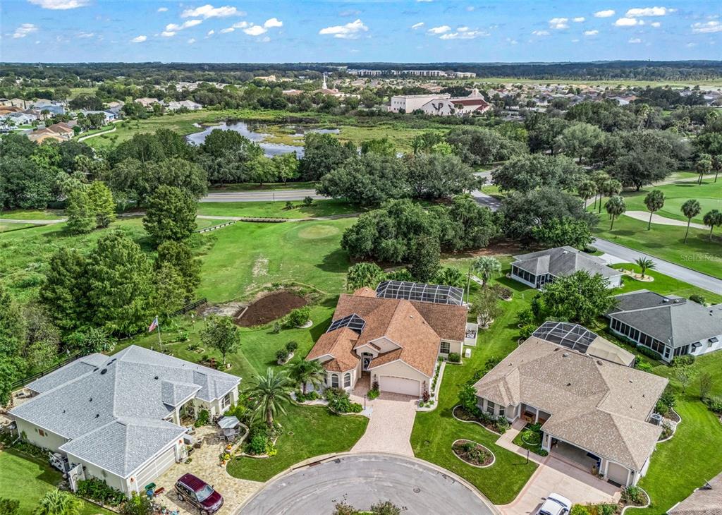 A screened-in patio features a paver floor, white gravel borders, and a view of the yard — 1802 ESTAFANA WAY, THE VILLAGES, FL